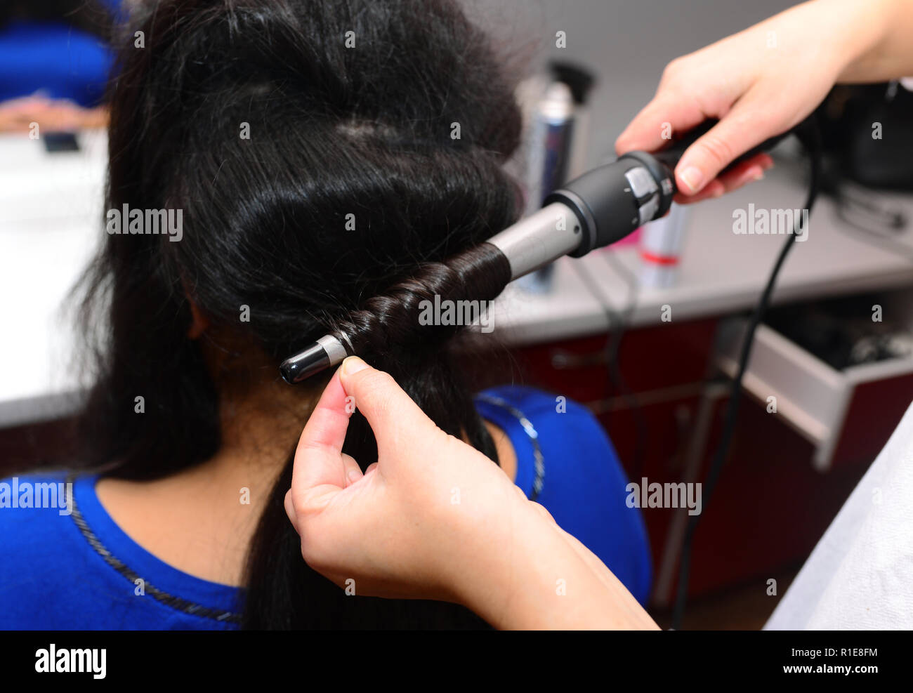 Hairstylist curling hair woman with electric iron Stock Photo - Alamy